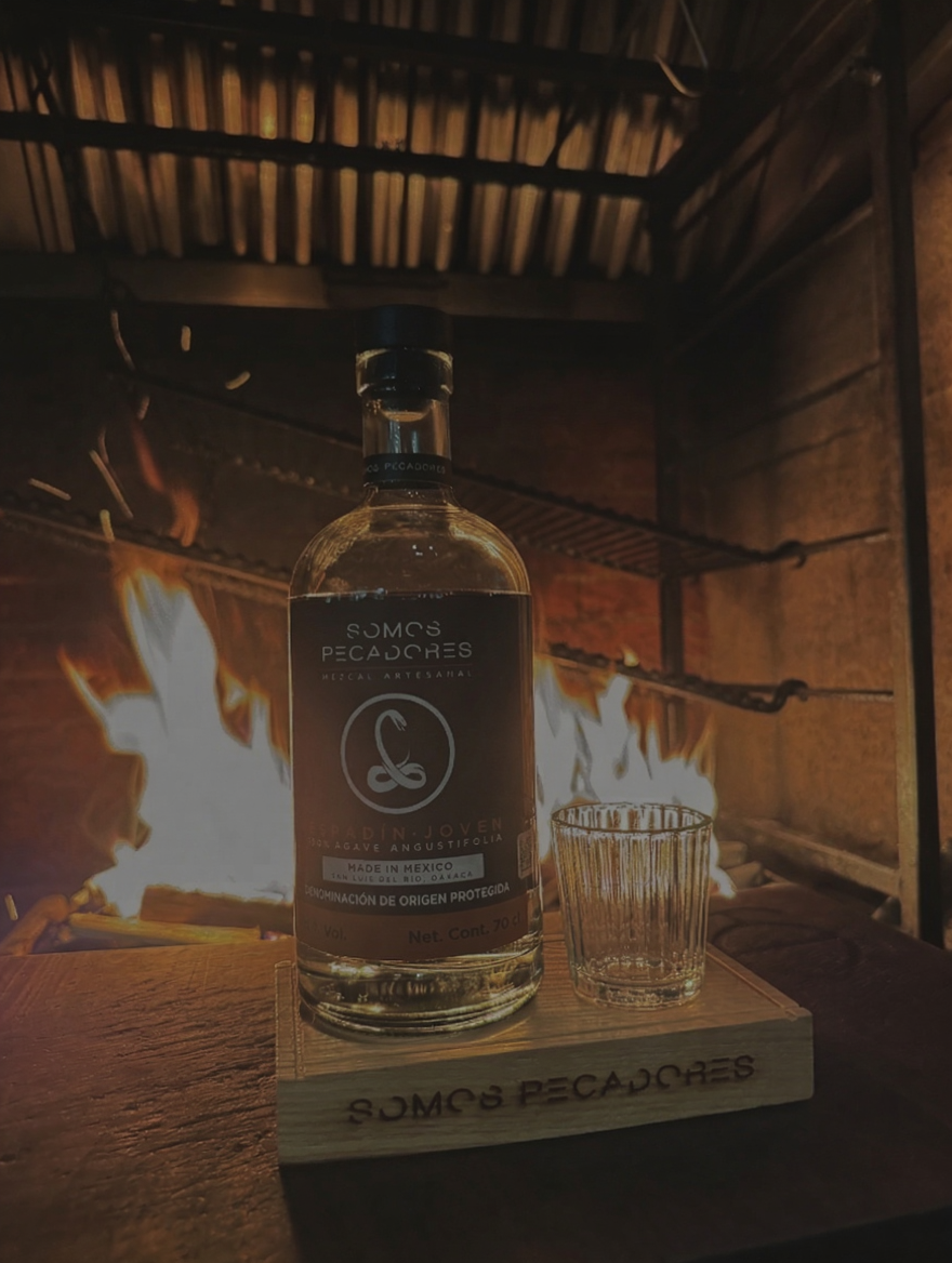 Somos Pecadores mezcal bottle by firelight — Difford's Guide 5-star rated